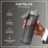 A dark gray water bottle with a full flip lid is being held. The lid folds back 240 degrees. The bottle is labeled “SLIM RECYCLON™”.