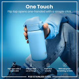 A light-blue stainless steel water bottle is held; its flip top opens one-handed. The bottle is shown against a blue background and being held by a person wearing blue jeans. 