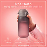 A pink water bottle, being held, features a one-handed flip top. The bottle is shown against a pink background with marketing text. 