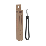 Black wrist strap hanging vertically with branded packaging nearby against a plain white background. Text on packaging: 