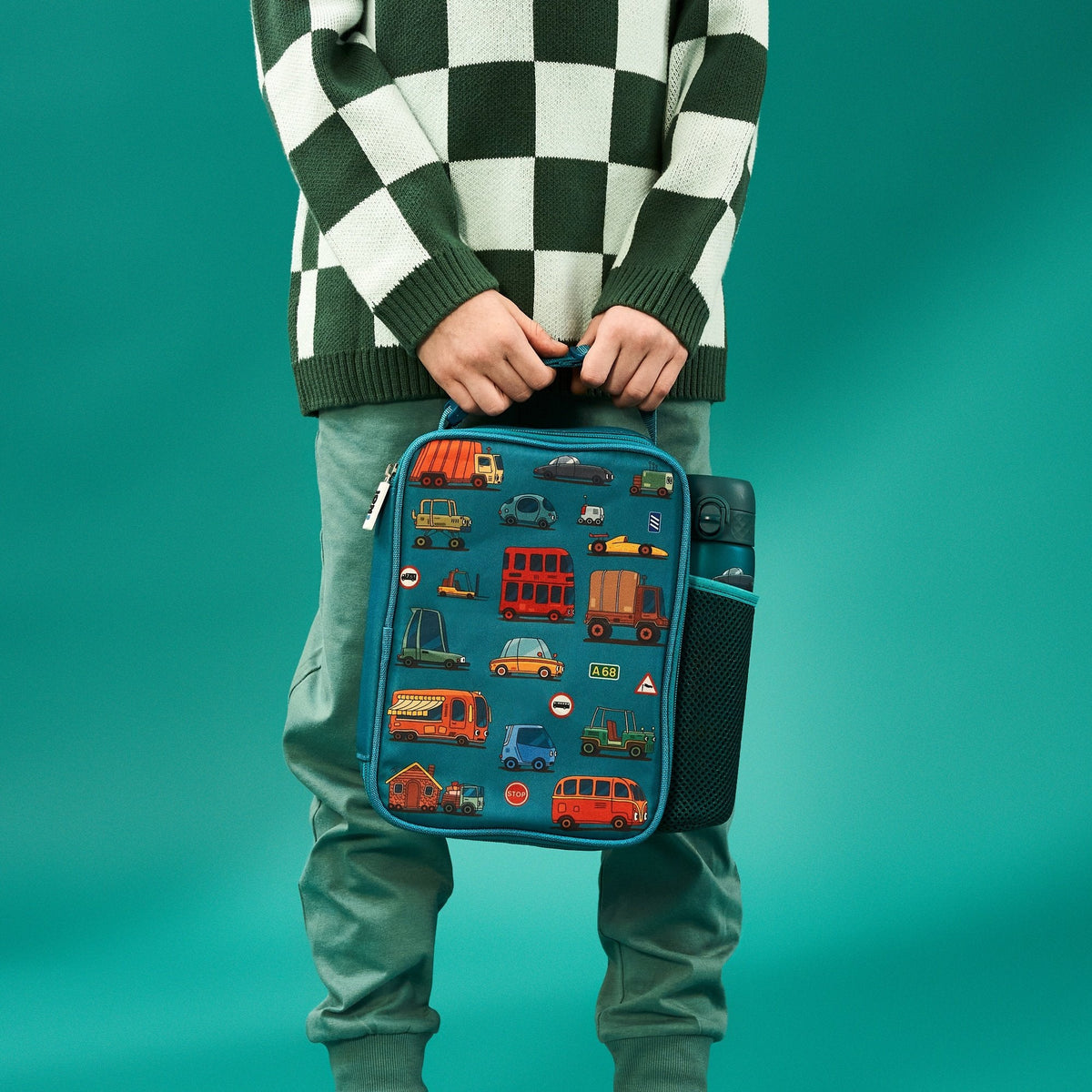 A rectangular teal lunchbox showcases colorful cartoon vehicles including cars, buses, and trucks with road signs such as "Stop" and "A68" in a playful pattern.