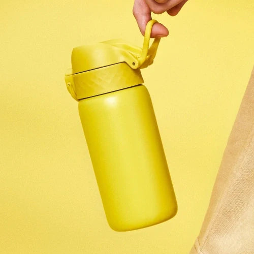 A yellow insulated water bottle is being held by a hand against a yellow background.
